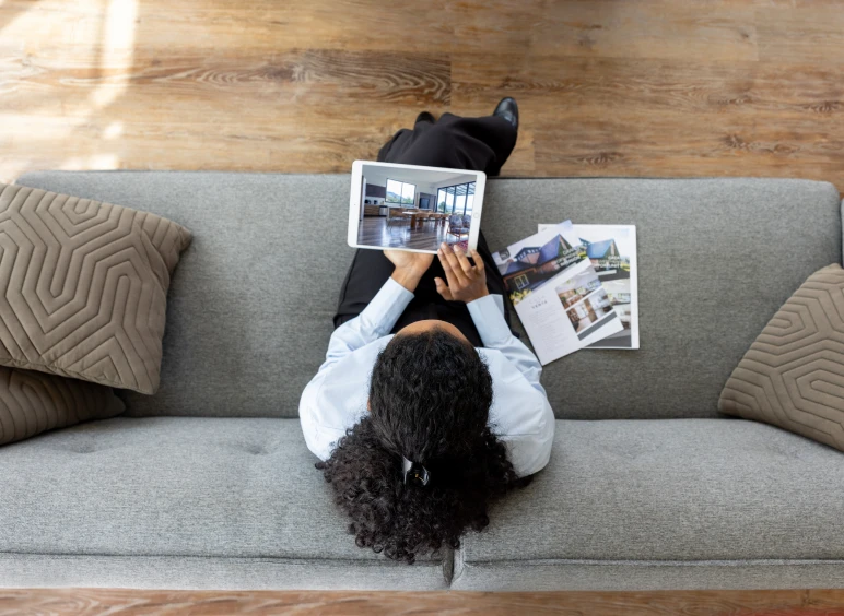 Individual exploring homes online on couch