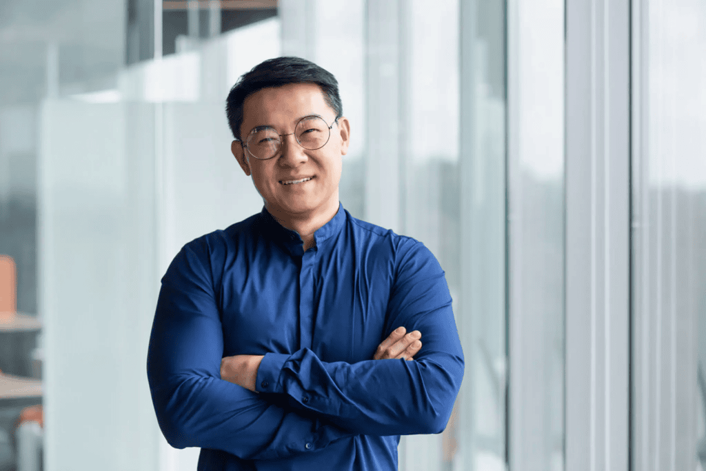 Smiling man in blue shirt, crossed arms.