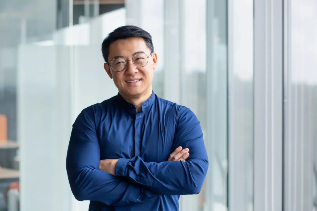 Smiling person in blue shirt, arms crossed.