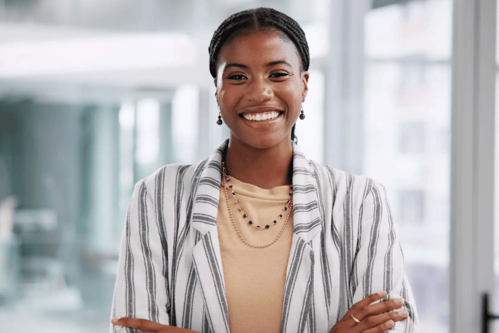 Smiling woman in striped blazer, crossed arms.